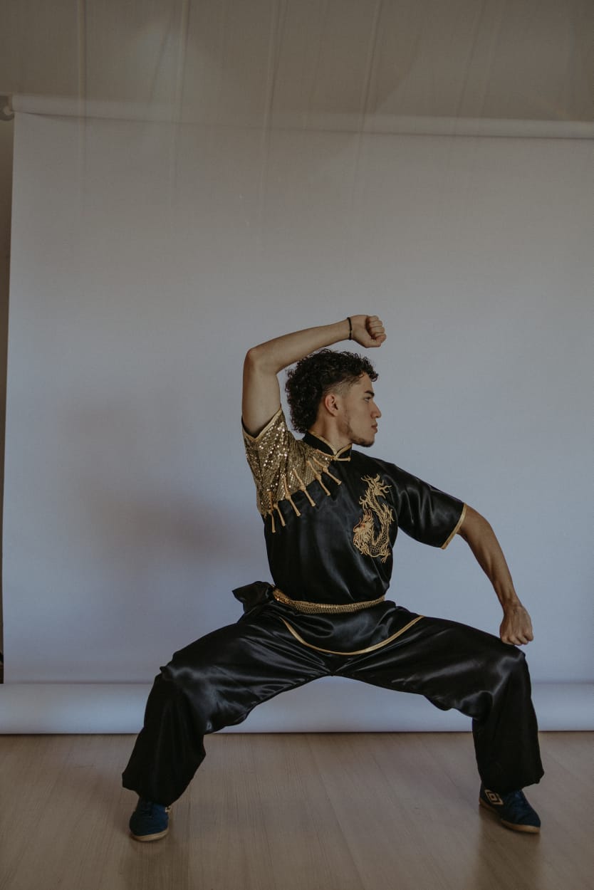 Aluno praticando postura de Kung Fu em um salão